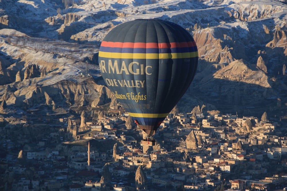 blue, yellow, and red air balloon flying near brown mountain