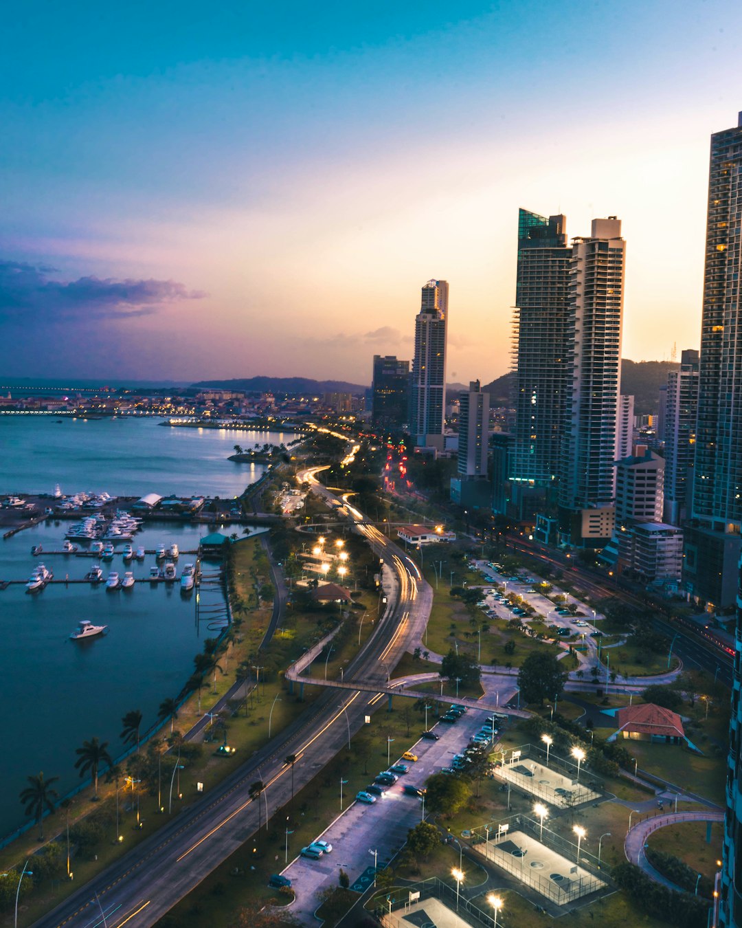 high rise buildings near body of water in distant of mountain