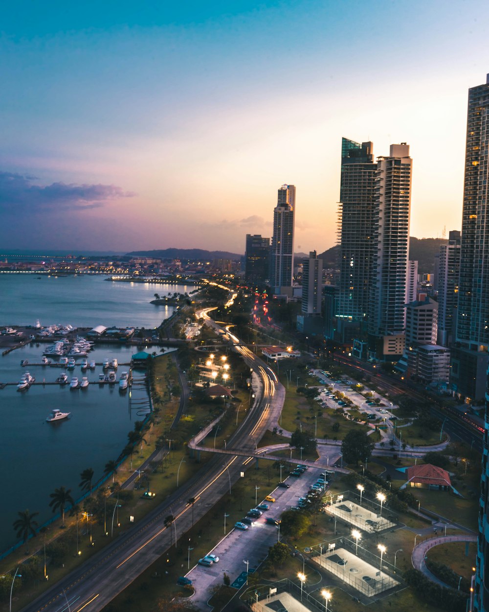 high rise buildings near body of water in distant of mountain