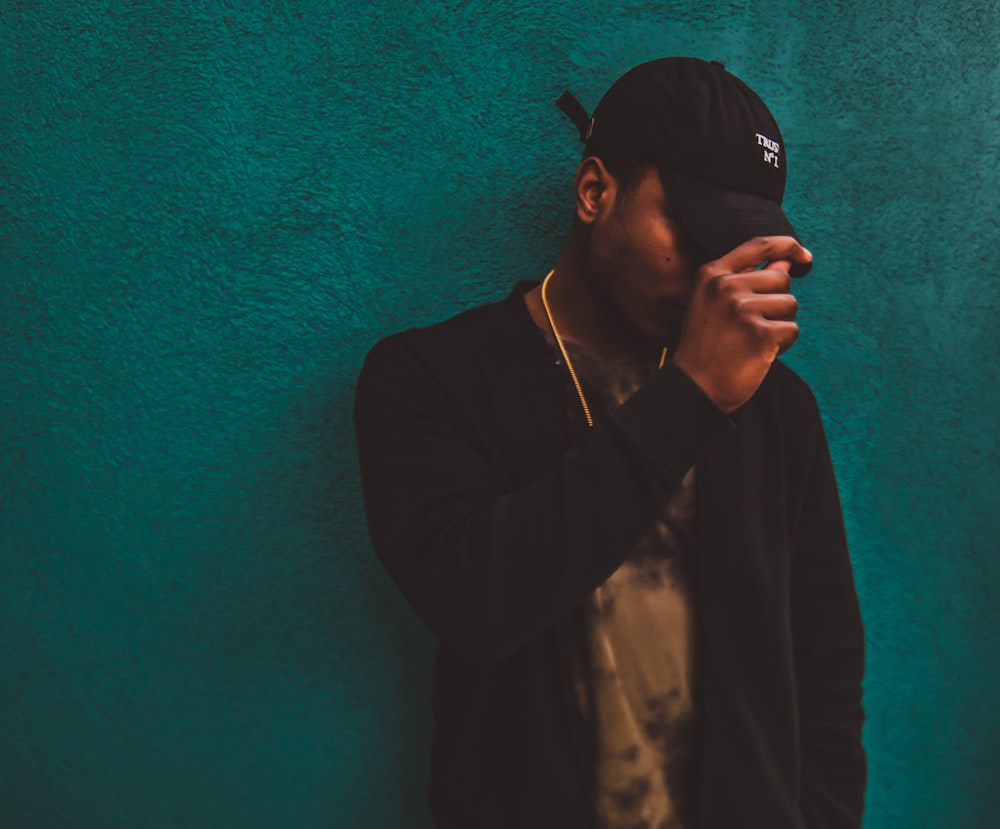 man leaning on green wall