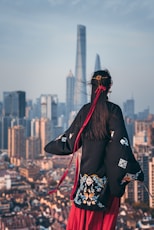 black haired woman in black coat staring at building during daytime