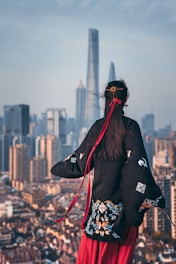 black haired woman in black coat staring at building during daytime