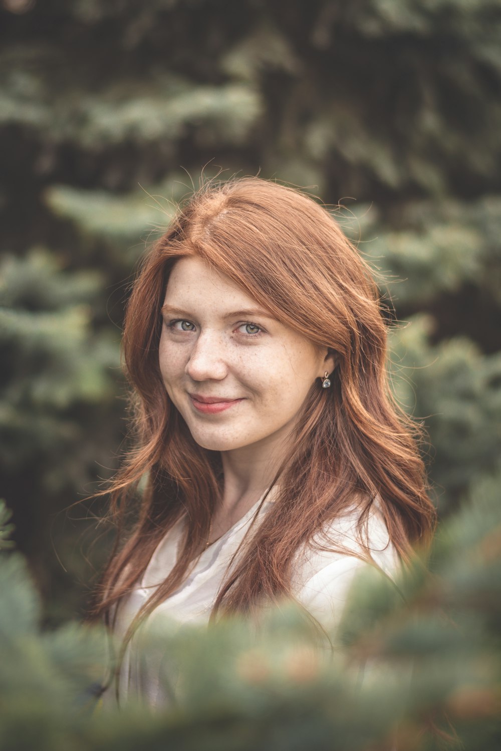 woman wearing white crew-neck shirt behind trees during daytime