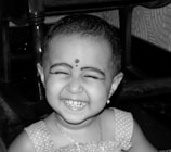 A little girl smiling brightly in the barber chair after her new haircut.