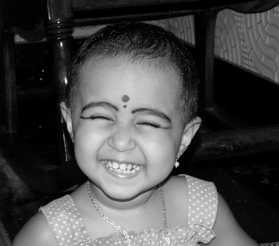 A little girl smiling brightly in the barber chair after her new haircut.