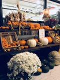 A large porch display with layered fall decor including woven baskets, dried leaves, and a variety of pumpkins in warm hues