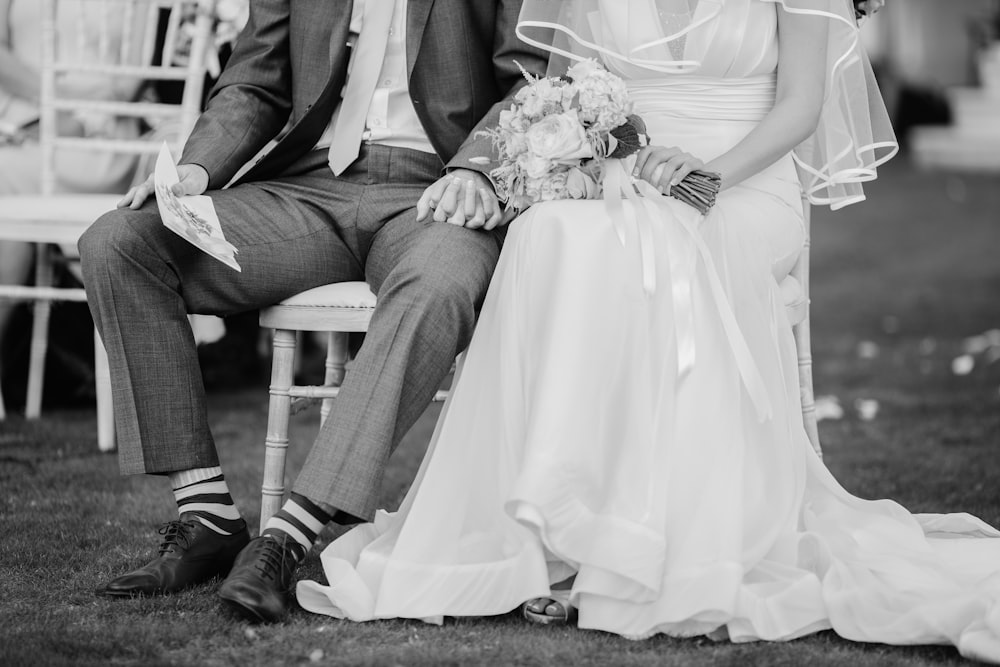greyscale photography of groom and bride sitting on chairs