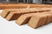 Rows of neatly stacked rectangular crackers with perforations are arranged on a white surface, creating a sense of repetition and order in the image.