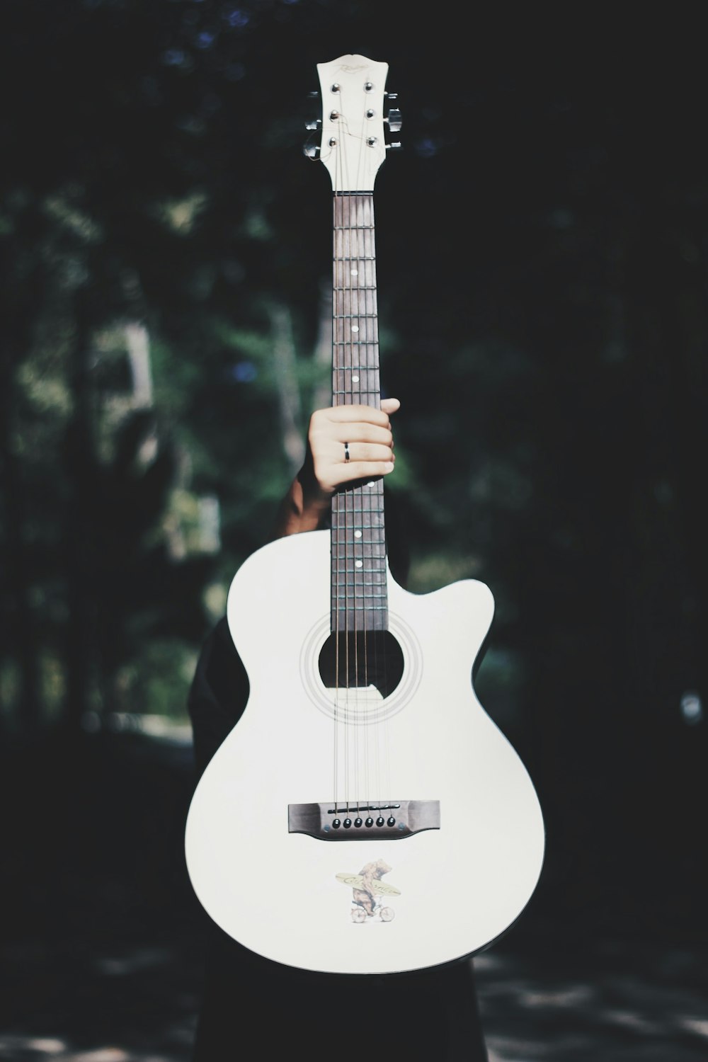 白いアコースティックギターを持つ人