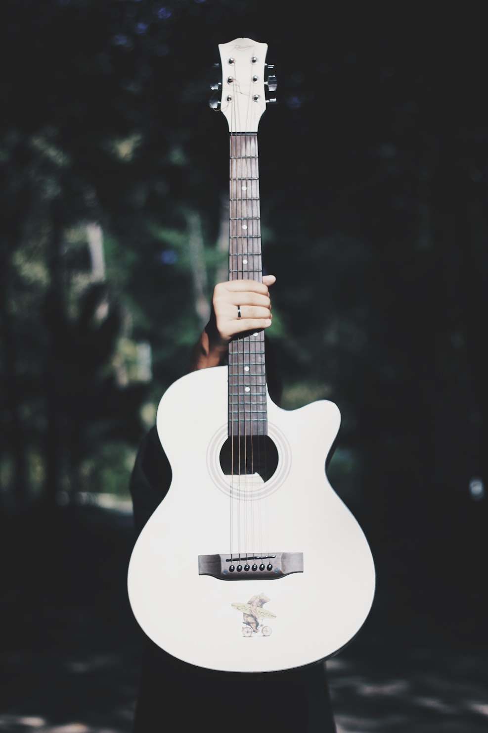 A person holding a white guitar