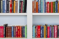 assorted-title book lot placed on white wooden shelf