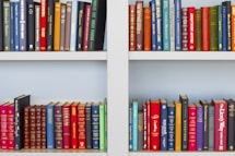 assorted-title book lot placed on white wooden shelf