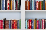 assorted-title book lot placed on white wooden shelf