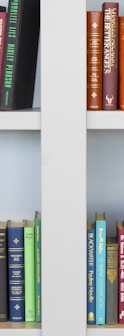 assorted-title book lot placed on white wooden shelf