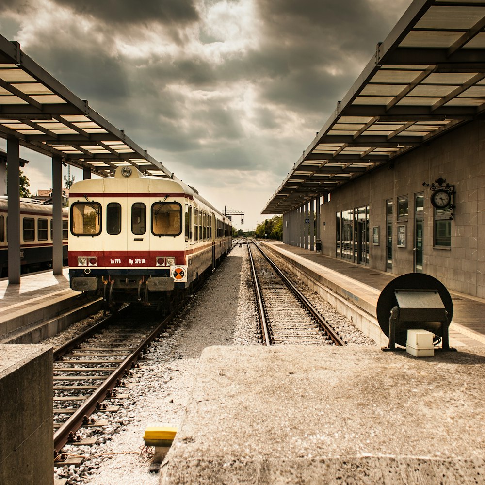 photo of white and red train station under grey cloudy sky