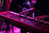 Keyboardist fingers dancing above keys with colorful background hues.
