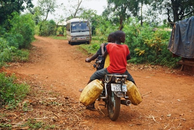 Children riding ATVs along a dirt trail surrounded by green fields.