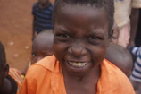 Children smiling brightly during a healthcare camp in a sunny outdoor setting