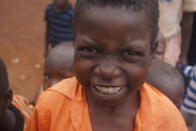 A cheerful young boy wearing a bright orange t-shirt and denim shorts playing outdoors