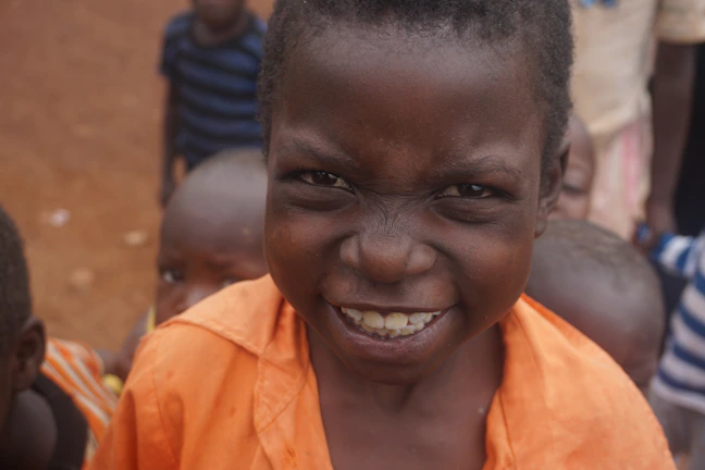 Children smiling brightly during a healthcare camp in a sunny outdoor setting