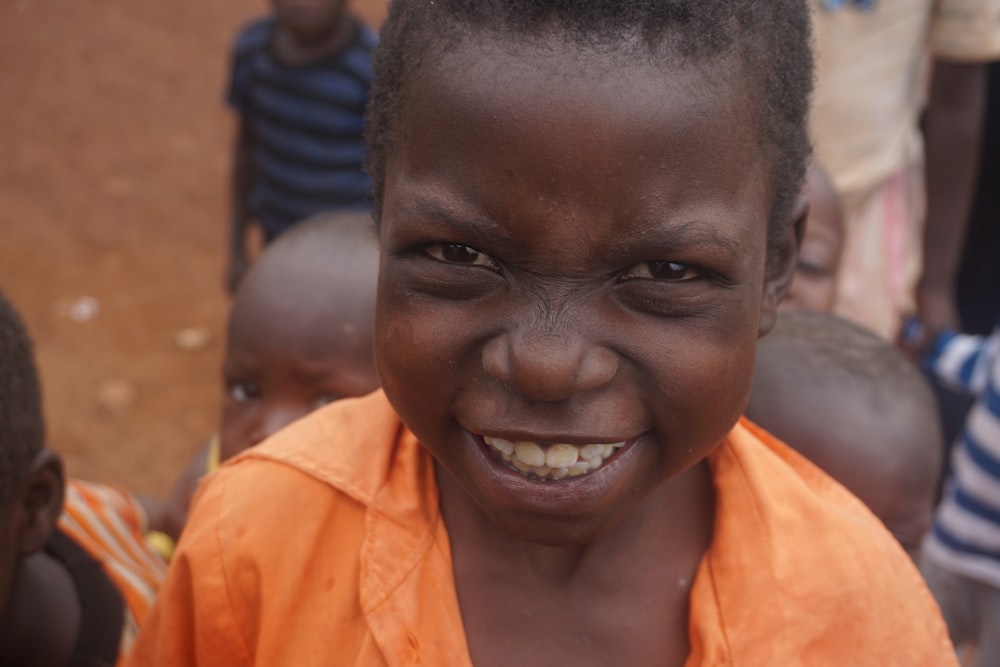 smiling boy in orange collar top during daytime