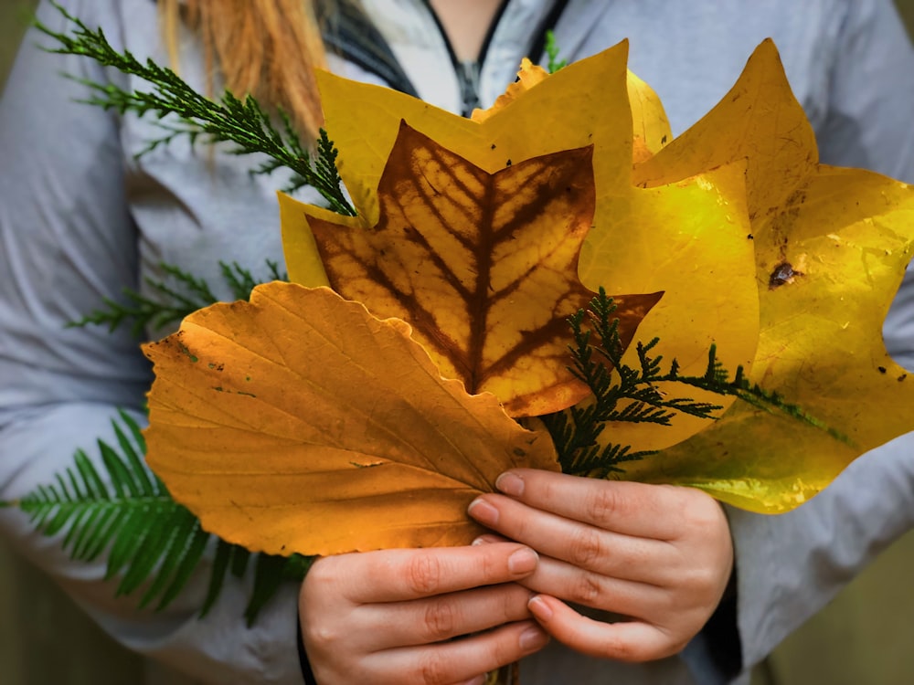 woman holding yellow leaves