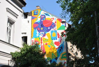 Vibrant large-scale mural on an urban building wall with dynamic shapes and rich colors.