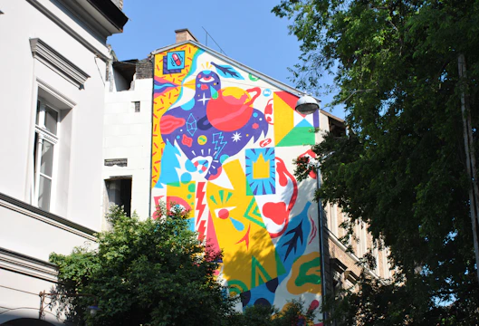 Vibrant large-scale mural on an urban building wall with dynamic shapes and rich colors.