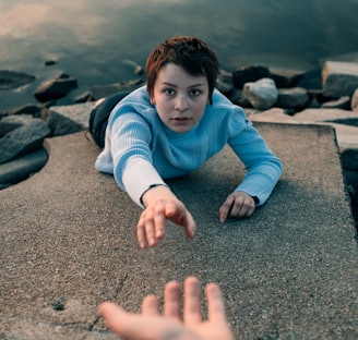 woman reaching hand above water during daytime photo