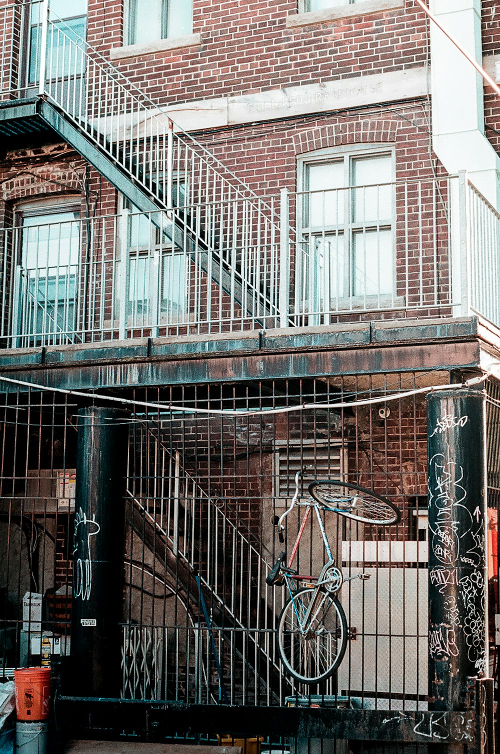 red and gray bicycle on metal railing on red concrete building at daytime