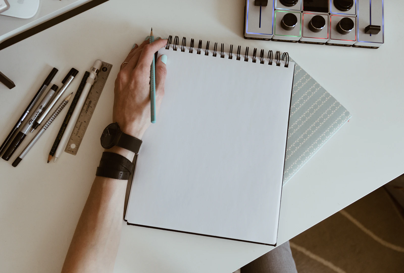 White spiral notebook with pens and a watch