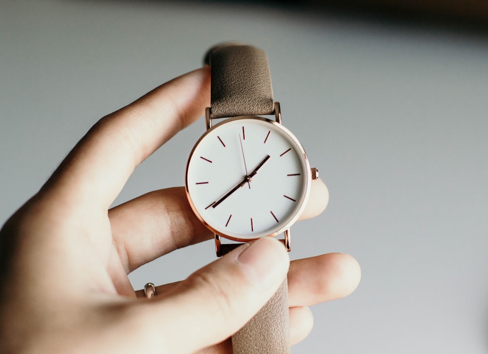 person holding analog watch