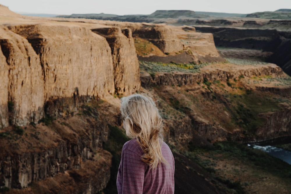 woman standing near brown mountain under blue sky