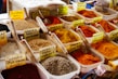 Close-up of colorful spices and grains in clear containers on market shelves.