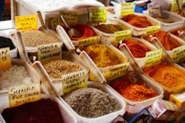 Assortment of colorful loose spices displayed in traditional Indian containers.