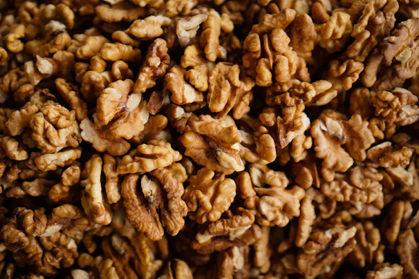 Close-up of a handful of glossy pecan nuts on a rustic wooden table