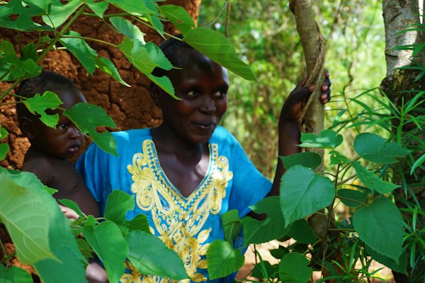 A woman among the leaves in a village outside the town — Jinja, Uganda