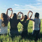 women forming heart gestures during daytime