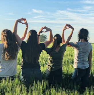 women forming heart gestures during daytime