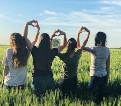 women forming heart gestures during daytime