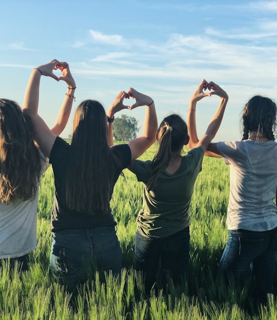 women forming heart gestures during daytime