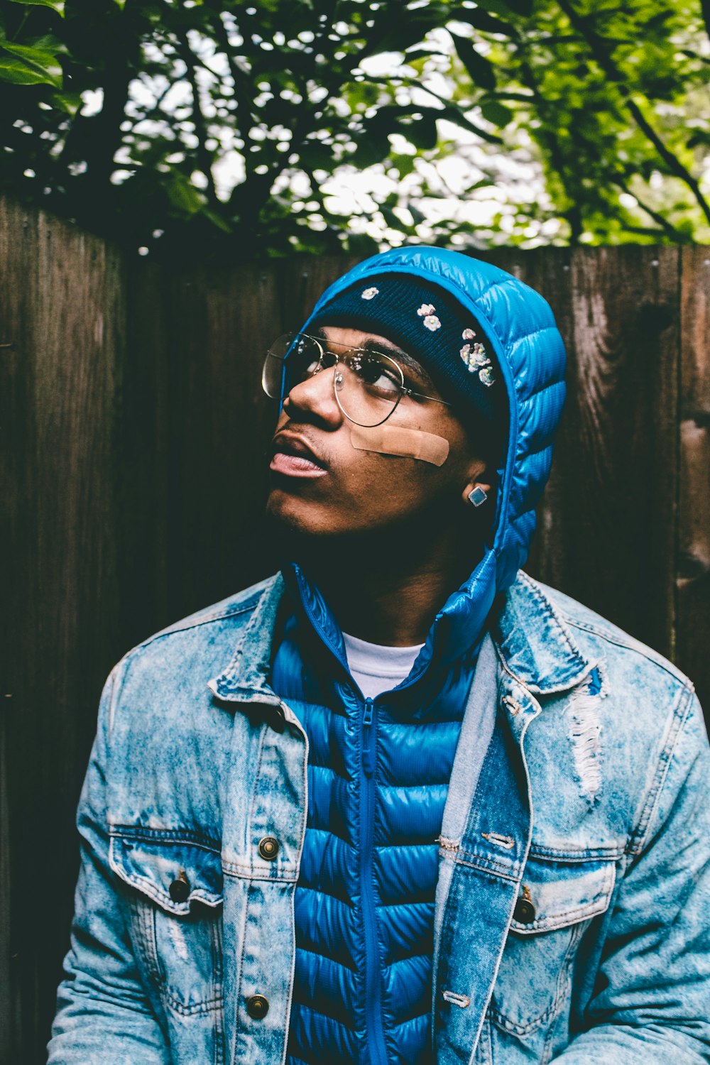 man looking above wearing blue bubble jacket and blue denim jacket