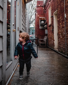 boy in black jacket walking looking at full-glass door