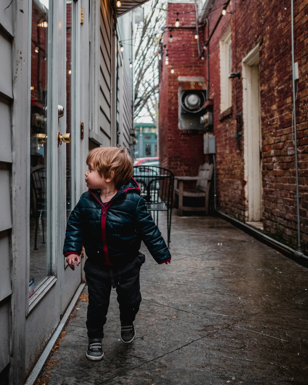 menino na jaqueta preta andando olhando para a porta de vidro cheio