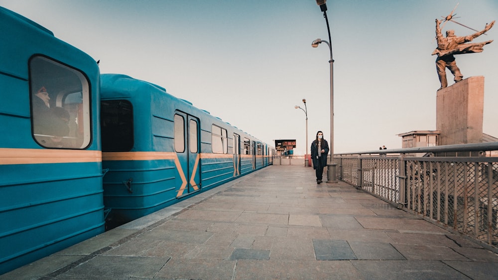 person walking near blue train during daytime