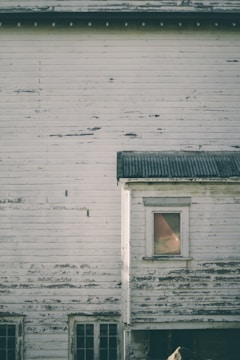A weathered house mid-renovation with fresh paint and new windows.