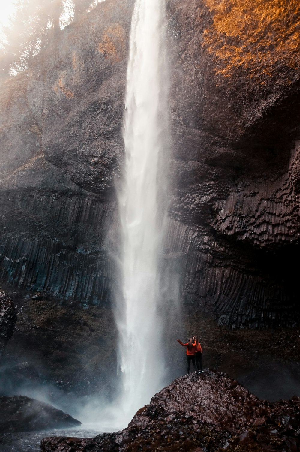 two person standing near waterfalls