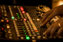 Close-up of a sound engineer adjusting audio levels on a mixing board.