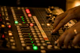 Close-up of hands adjusting audio mixer dials at a cozy home studio
