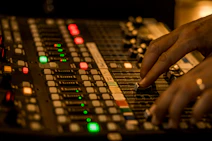 Close-up of hands adjusting audio levels on a sleek digital mixing board.